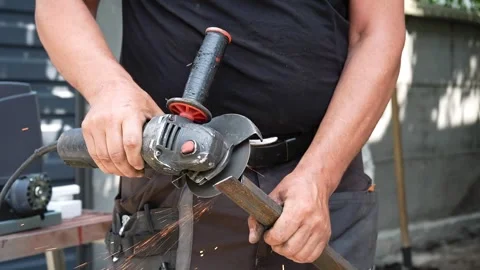 Worker cutting metal tube using an Angle Grinder. Bright sparks and flashes Stock Footage 258645633