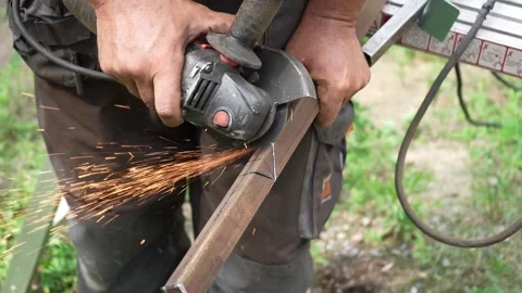 Worker cutting metal tube using an Angle Grinder. Bright sparks and flashes Stock-Footage 258645857