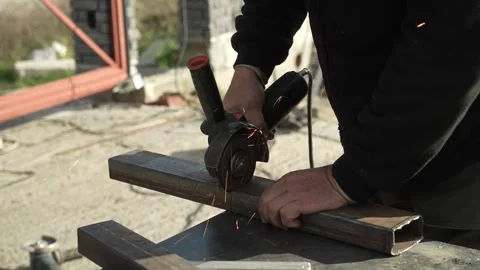 Worker cutting metal tube using an Angle Grinder. Bright sparks and flashes Stock Footage 259027381