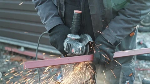 Worker cutting metal tube using an Angle Grinder. Bright sparks and flashes Stock Footage 261528268