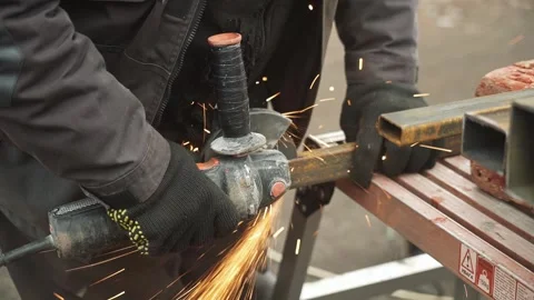 Worker cutting metal tube using an Angle Grinder. Bright sparks and flashes Stock Footage 261528289