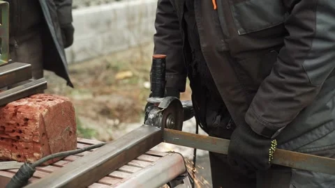 Worker cutting metal tube using an Angle Grinder. Bright sparks and flashes Stock Footage 261528376