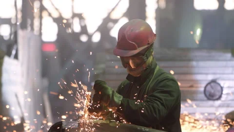 A Worker is cutting the metal using the Grinder Tool at the Steelworks Factory Stock Footage 159943520