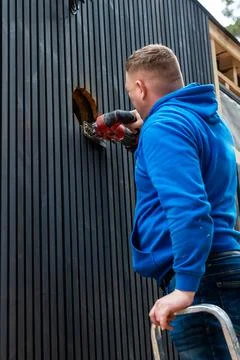Worker Cutting Paneling on Building Under Construction with Power Tool Stock Photos