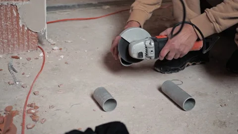 Worker cutting PVC pipes using angle grinder at construction site. Laying pipes Stock Footage 234549159