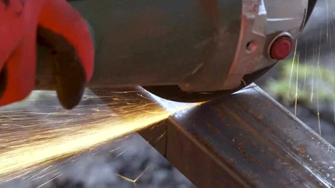 Worker cutting rectangular steel tube with an angle grinder tool creating sparks Vidéo 262803196