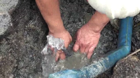 A worker is cutting with a saw a portion of a pipe that is broken. Stock Footage 69275595