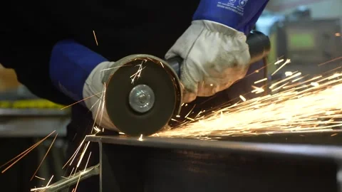 Worker cutting steel with a angle grinder in a workshop Stock Footage 256087482