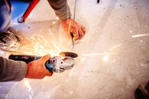 Worker cutting steel bars using manual grinder Stock Photos