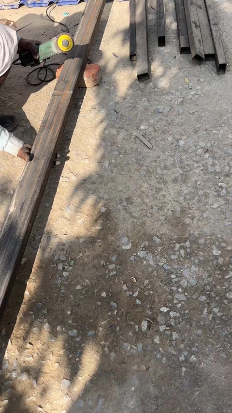 Worker Cutting Steel Pipe with Angle Grinder at Construction Site Stockbeeldmateriaal 324008405