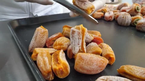 Worker Cutting Sweet Dried Persimmon Slices with Scissors on Metal Tray Stock Footage 345291831
