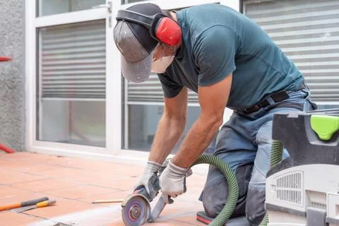 Worker cutting tile with angle grinder on outdoor patio surface 스톡 사진