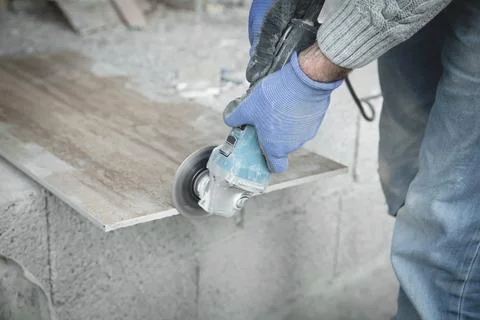 Worker cutting a tile with a grinder. Stock Photos