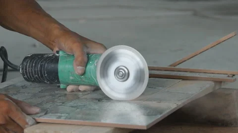 Worker cutting a tile using an angle grinder at construction site Video stock 63311272