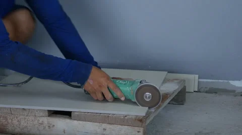 Worker cutting a tile using an angle grinder at construction site Video stock 63348862