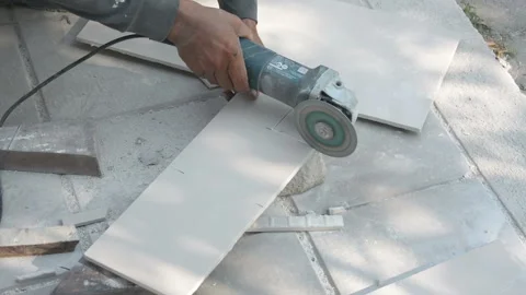 Worker cutting a tile using an angle grinder at construction site Stock Footage 238909408