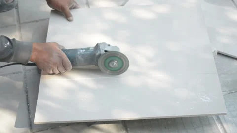 Worker cutting a tile using an angle grinder at construction site Stock Footage 238909435