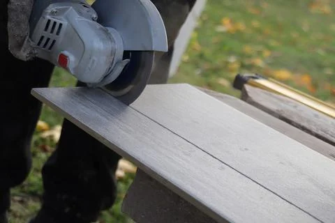 Worker cutting a tile using an angle grinder at construction site Stock Photos