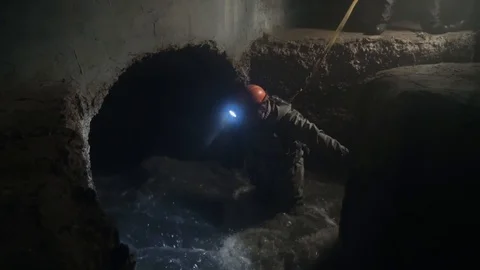 Worker in dark city sewage with large water flow. Stock Footage 104186367