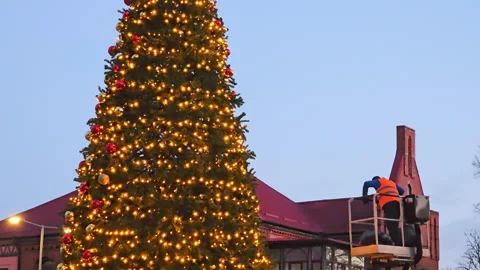 A worker decorates the Christmas tree on the city square Stock Footage 267179617