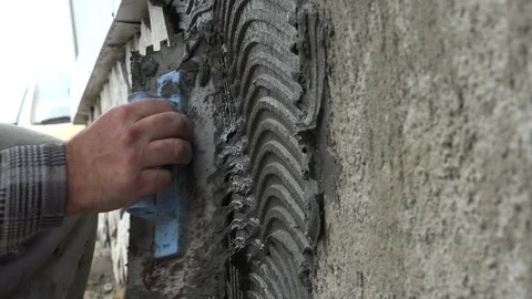 Worker decorating a wall with ornamental stone tiles pressing and fixing a tile Video stock 96257086