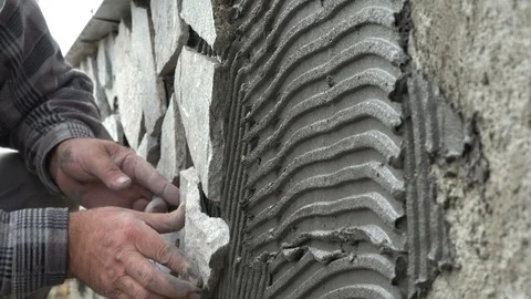Worker decorating a wall with ornamental stone tiles pressing and fixing a tile Stock Footage 96257115