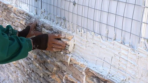 Worker decorating a wall with ornamental stone tiles pressing and fixing a tile Stock Footage 97289166