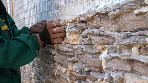 Worker decorating a wall with ornamental stone tiles pressing and fixing a tile Stock Footage 97289172
