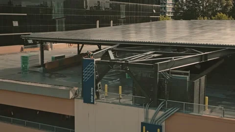 Worker descending ladder from solar canopy framework generating green power 库存影片 333944701