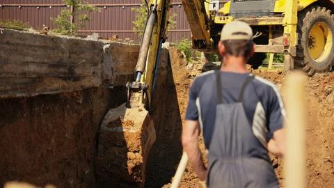 Worker digging trench with excavator at construction site Stock Photos