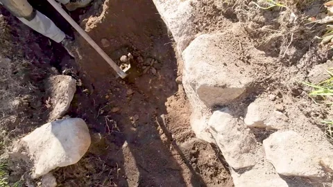 A worker digging a trench with a hoe in the ground, Manual Labor Stock Footage 316761327