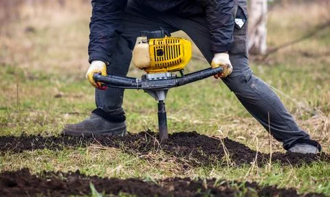 Worker digs the ground with a gasoline blower in the garden Stock Photos