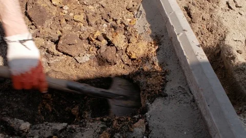 Worker digs the ground with a shovel under the concrete curb Stock Footage 107935434