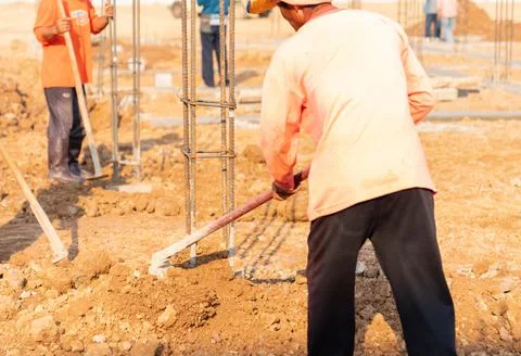 Worker digs soil with spade prepare around pole stucture. Stock Photos