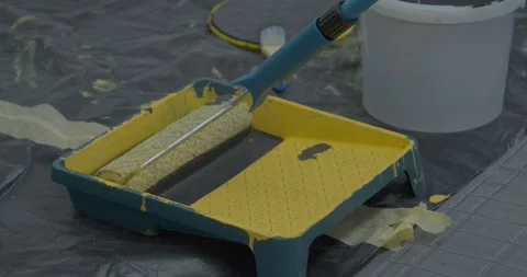 Worker dips roller into container with dense dark grey paint Stock Footage 169632093