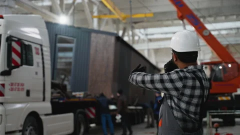 Worker directing modular home loading onto truck via radio Stock Footage 301823531