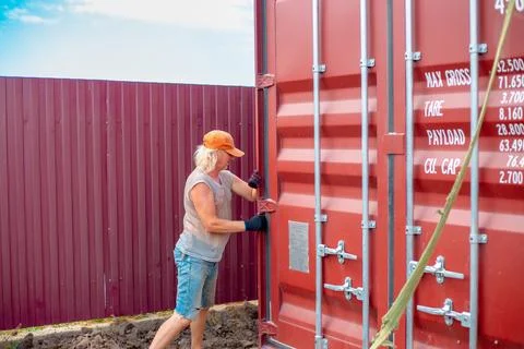 A worker directs a cargo container being lowered into place at its destination Stock Photos