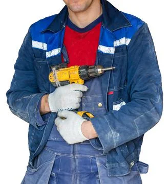 Worker in dirty uniform and protective gloves with drill in his hand in the room Stock Photos