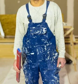 Worker in dirty uniform or boilersuit  with water level and palette-knife in hi Stock Photos