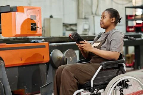 Worker with disability in factory on the machine Stock Photos