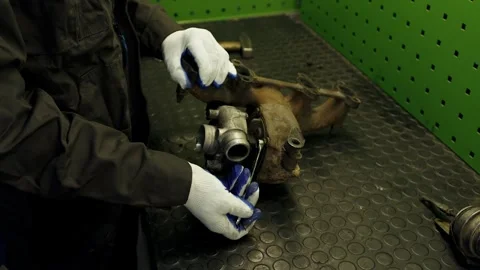 Worker disassembles for repair old rusty car turbine turbocharger Stock Footage 285643499