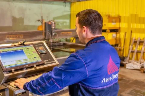 A worker does the setting up of a waterjet machine. The operator controls the Stock Photos