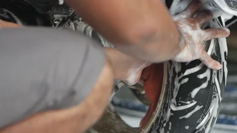Worker doing detailed cleaning and washing a motorbike with foam soap in car Stock-Footage 197555321