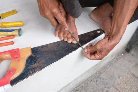 A Worker Doing Sharpening Tool of His Old Rusty Saw Tooth in Manual Process Stock-Fotos