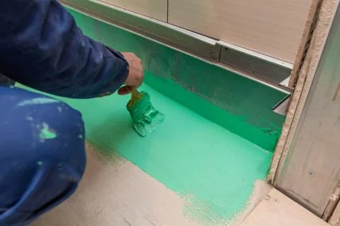 Worker is doing waterproof finish the bathroom floor in apartment is inder Stock Photos