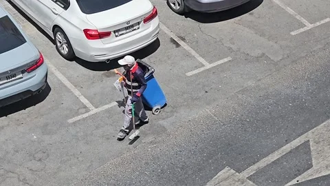 A worker, dressed in uniform and a cap, pushing a cleaning cart 스톡 동영상 311590795