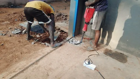 Worker Drilling Concrete With Jackhammer. Man Shoveling Mud From The Dug Ground  Video stock 122202188