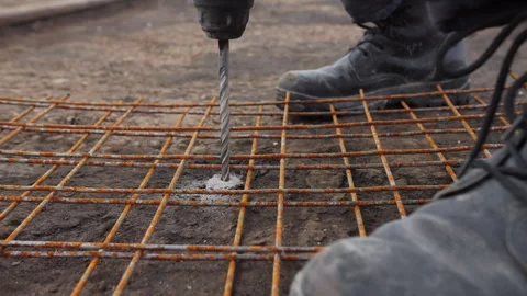 Worker drilling concrete under reinforcement mesh Stock Footage 310950725