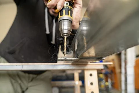 Worker drilling a hole in metal using power tool Stock Photos