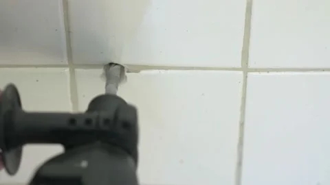 Worker drilling hole in white ceramic tiles on wall of bathroom Video stock 194395416